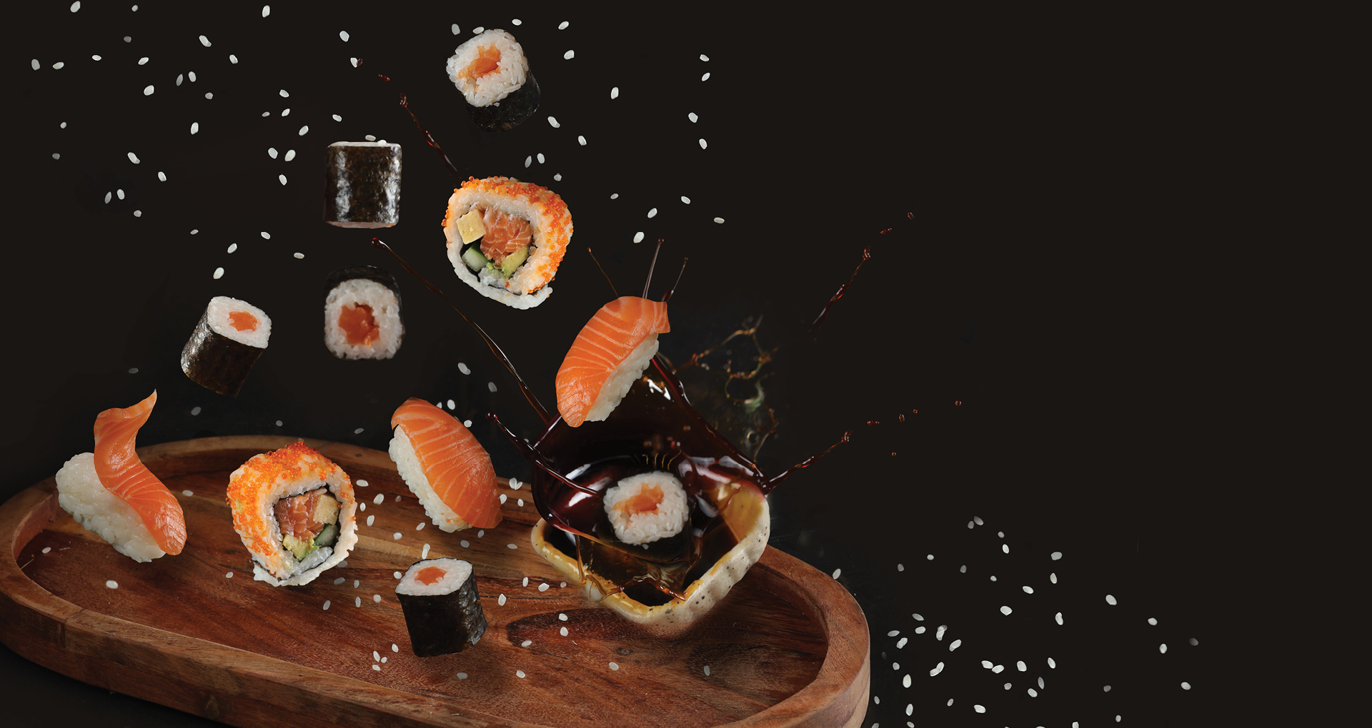 Fresh sushi rolls arranged on a wooden board with wasabi and pickled ginger